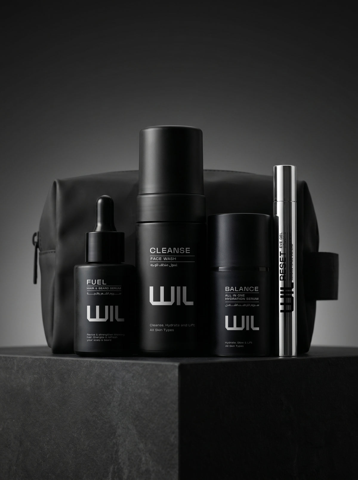 Full set of WIL products, including Cleanse face wash, Balance serum, Reset eye gel and Fuel hair and beard serum, arranged in front of WIL branded pouch on a dark gray pedestal against a dark gray background.